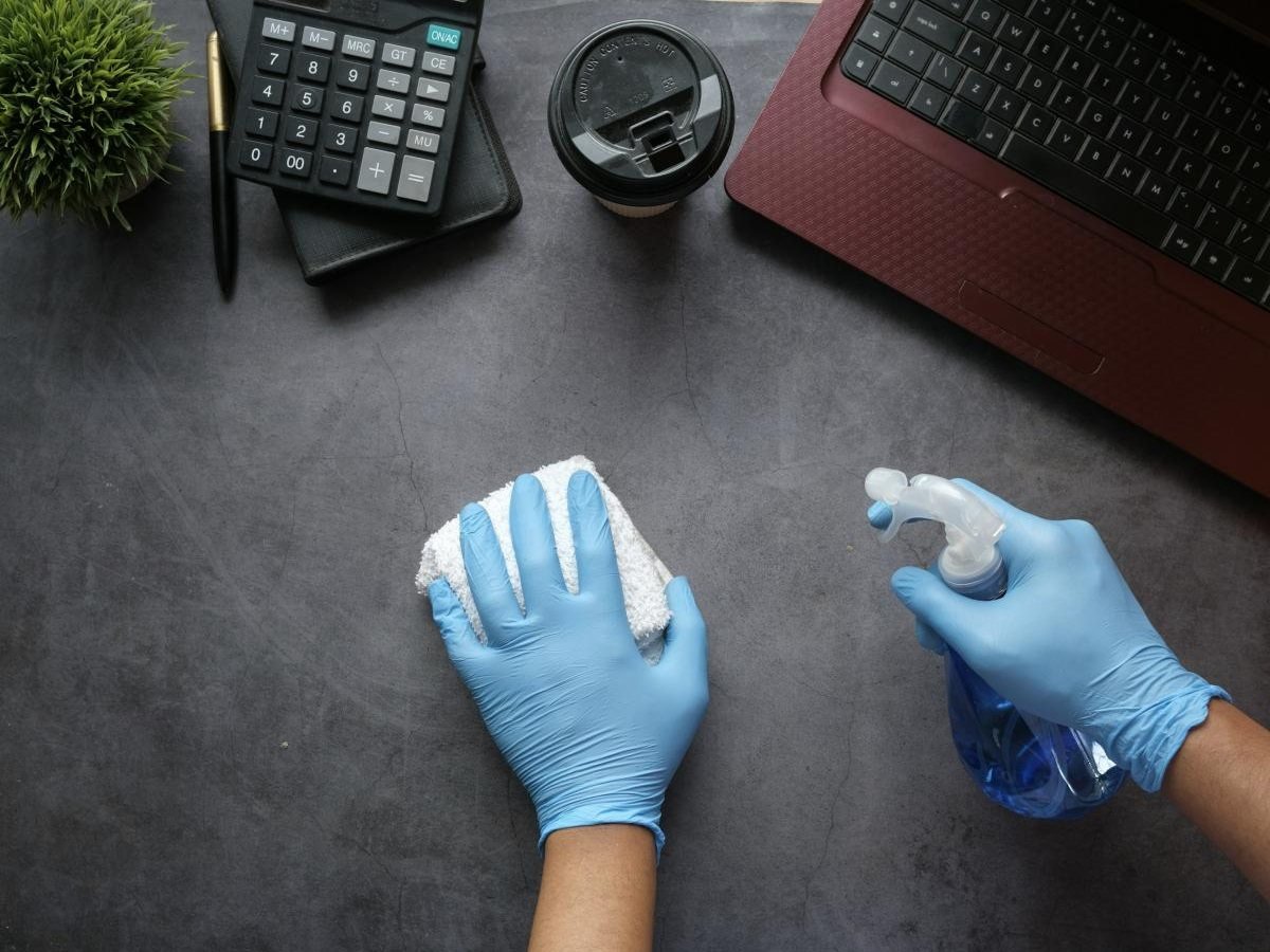 Mains gantées qui nettoient un bureau